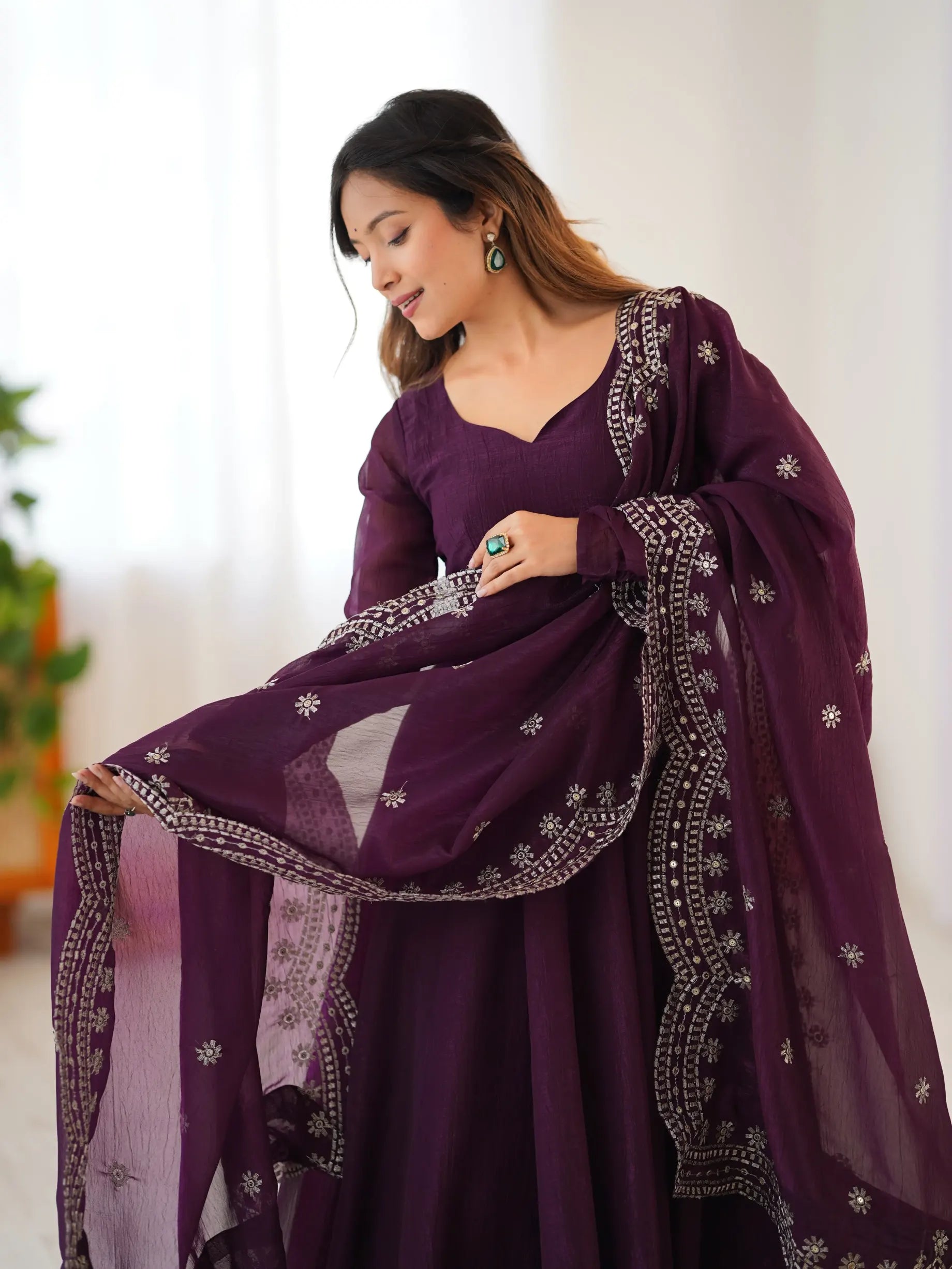 Woman wearing a purple traditional outfit with intricate designs indoors.