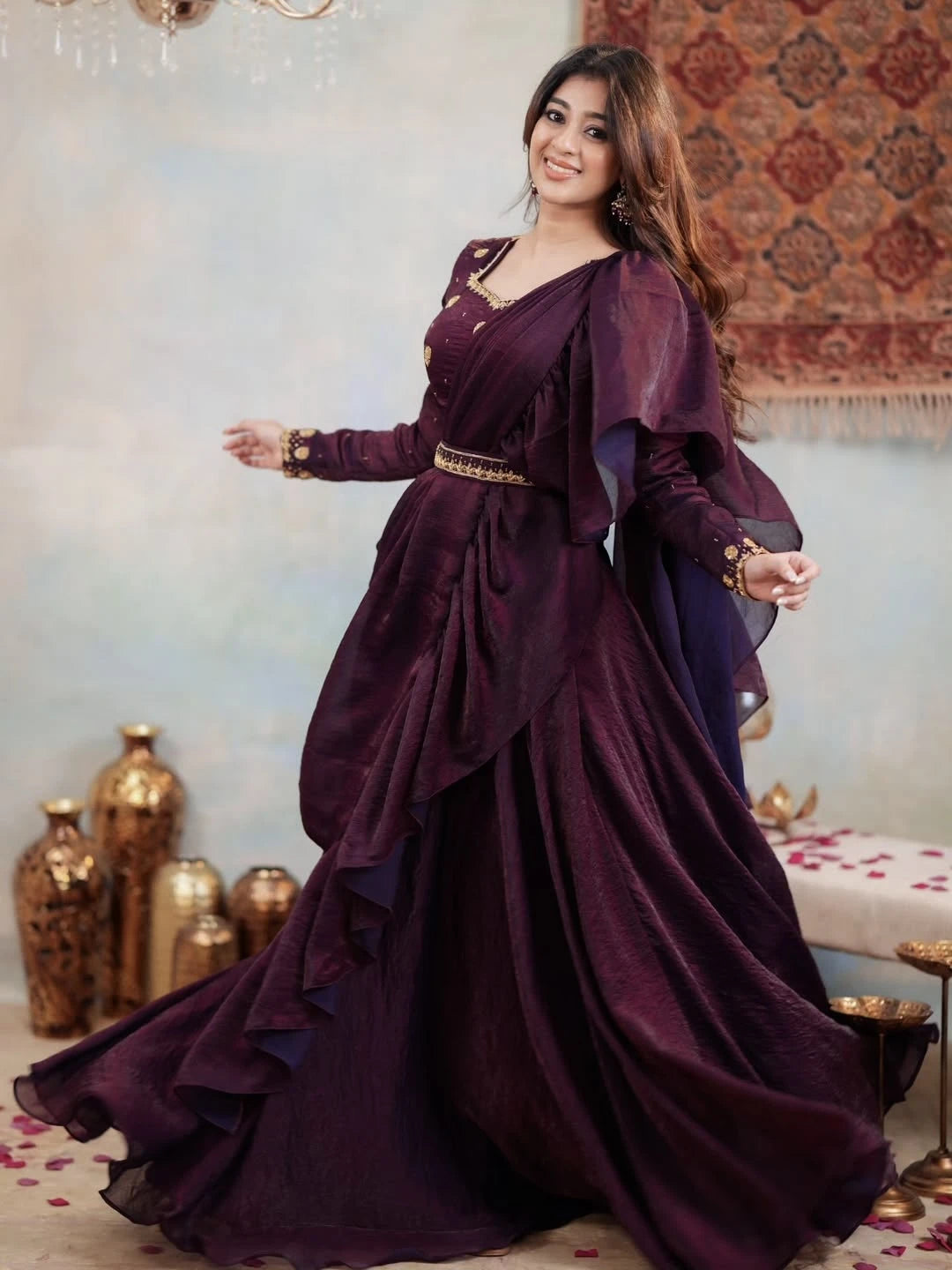 Woman in a long, dark purple dress with gold accents in an indoor setting.