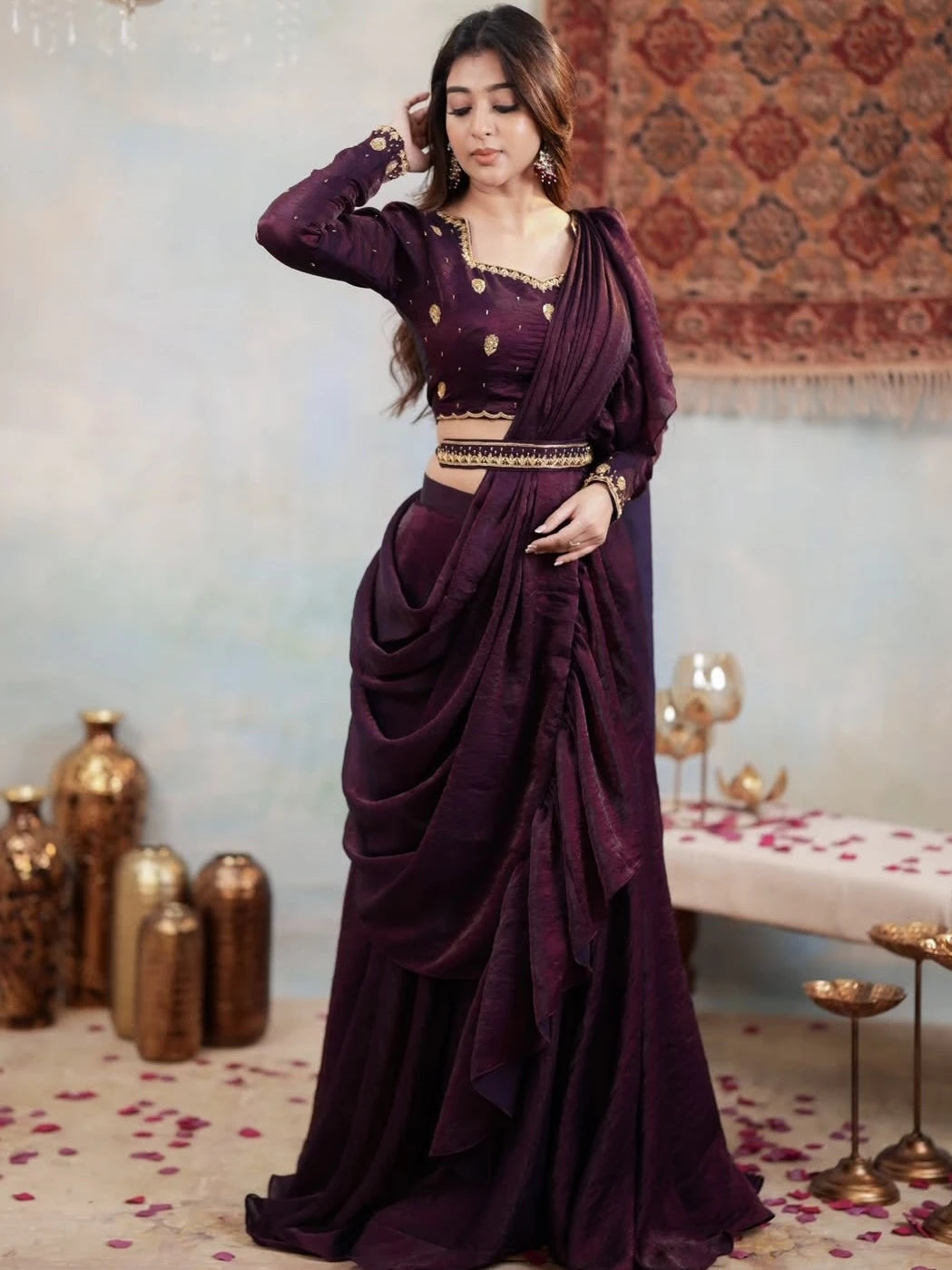 Woman in a purple saree with gold details in an elegant indoor setting