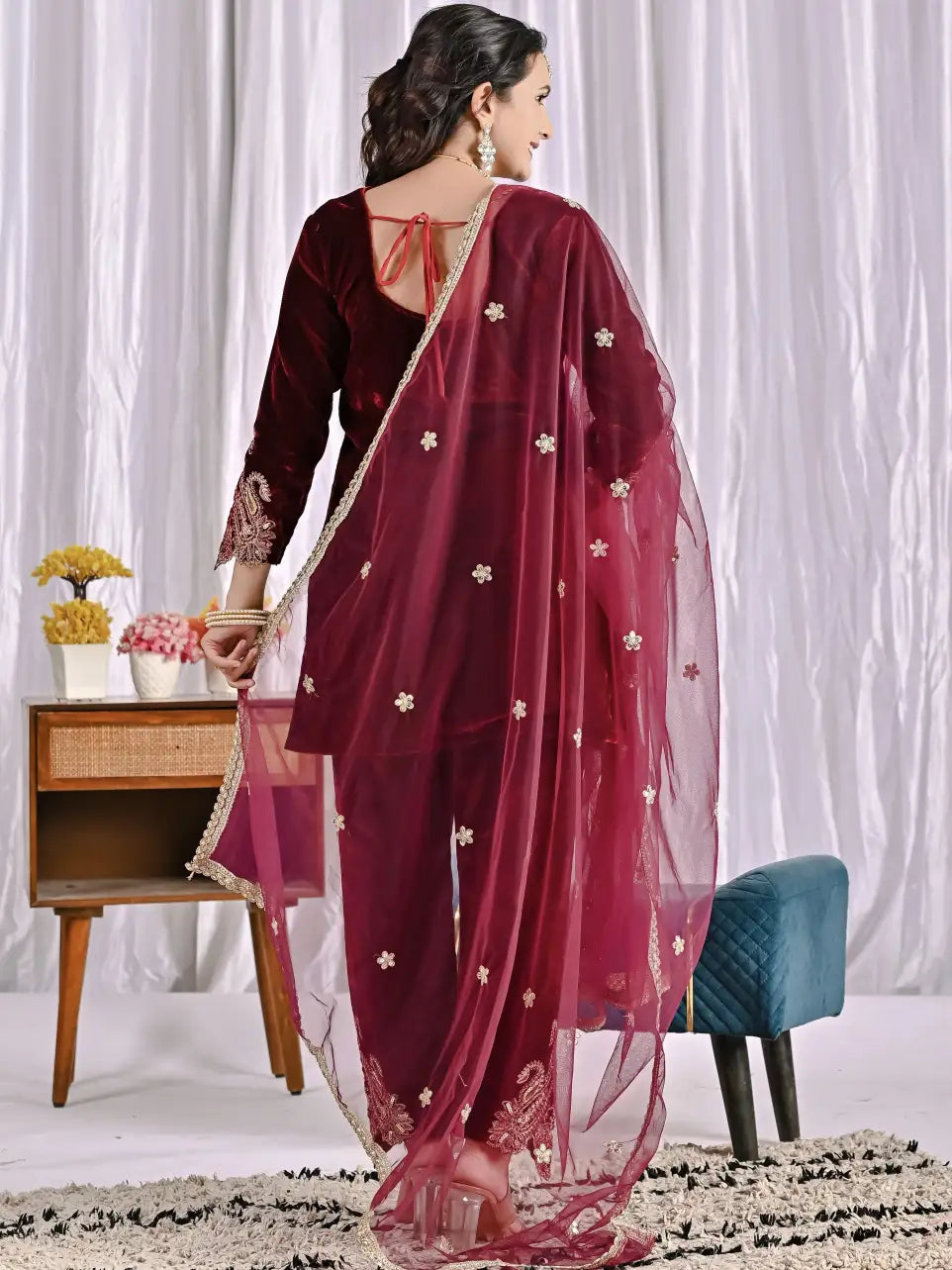 Woman wearing a winw traditional outfit with a matching dupatta in a room setting.