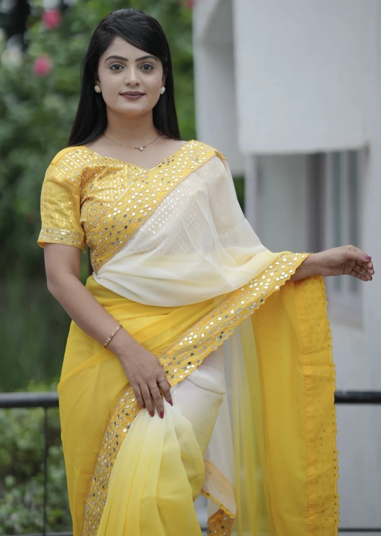 Woman wearing a yellow and white saree with a blurred background