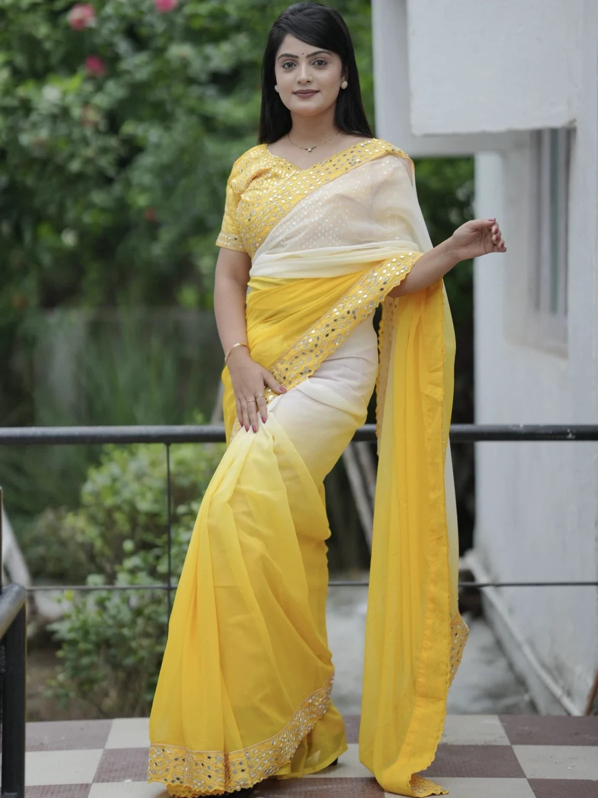 Woman wearing a yellow saree with white blouse in an outdoor setting